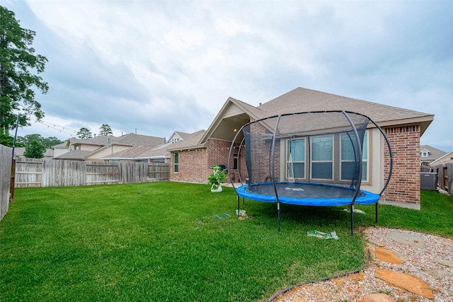 2625 Blooming Field Ln, Conroe, TX 77385 - rear view of house featuring brick siding, a trampoline, and roof with shingles