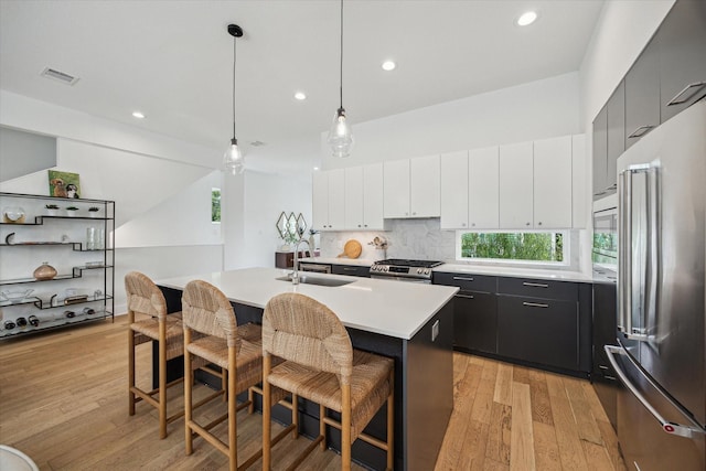 1234 W 25th St Unit A, Houston, TX 77008 - kitchen with stainless steel appliances, a sink, light wood finished floors, light countertops, and a kitchen bar