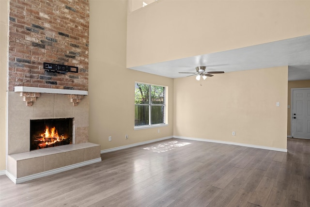6639 Feather Creek Dr, Houston, TX 77086 - unfurnished living room with wood finished floors, baseboards, a tile fireplace, and a ceiling fan