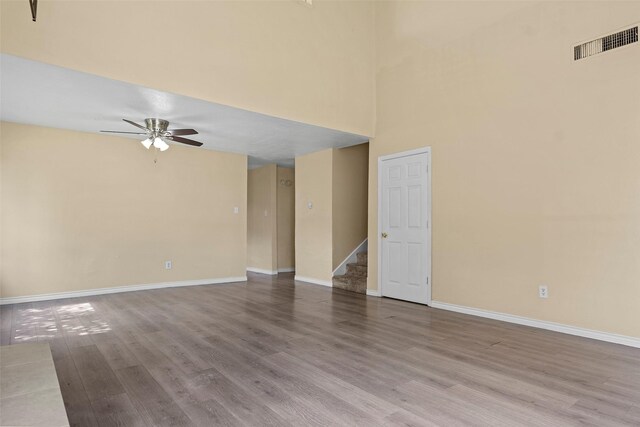 6639 Feather Creek Dr, Houston, TX 77086 - empty room featuring ceiling fan, wood finished floors, stairs, baseboards, and a towering ceiling
