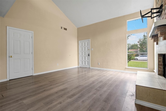 6639 Feather Creek Dr, Houston, TX 77086 - unfurnished living room featuring high vaulted ceiling, a fireplace with flush hearth, wood finished floors, and baseboards