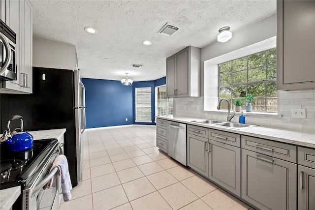 4131 N New Meadows Dr, Sugar Land, TX 77479 - kitchen with a sink, appliances with stainless steel finishes, gray cabinetry, decorative backsplash, and a textured ceiling