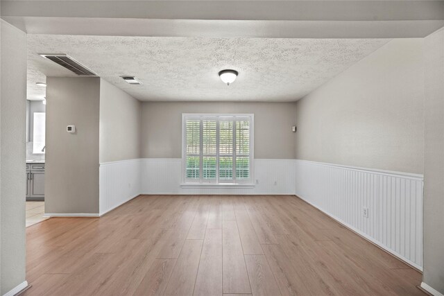 4131 N New Meadows Dr, Sugar Land, TX 77479 - unfurnished room with a wainscoted wall, light wood-type flooring, and a textured ceiling