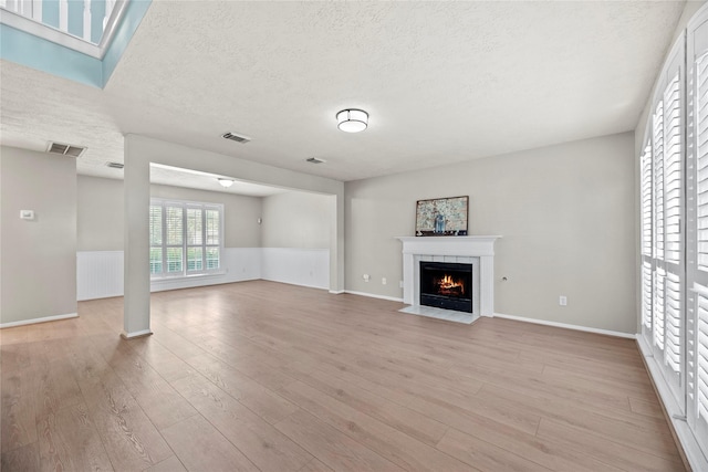 4131 N New Meadows Dr, Sugar Land, TX 77479 - unfurnished living room featuring a textured ceiling, a fireplace with flush hearth, light wood-style flooring, and baseboards