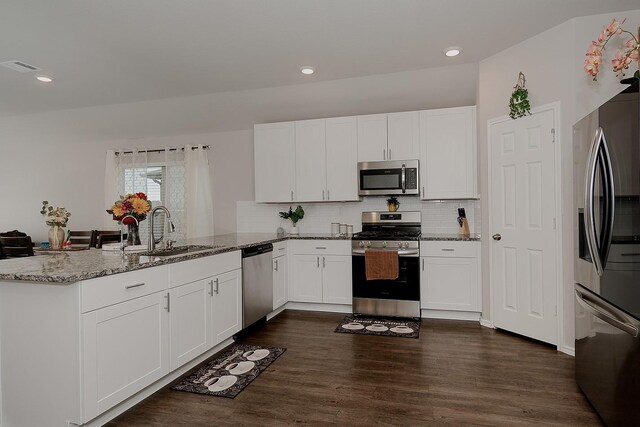 309 Cumberland Forest Dr, Magnolia, TX 77354 - kitchen featuring stainless steel appliances, a peninsula, light stone counters, a sink, and white cabinetry