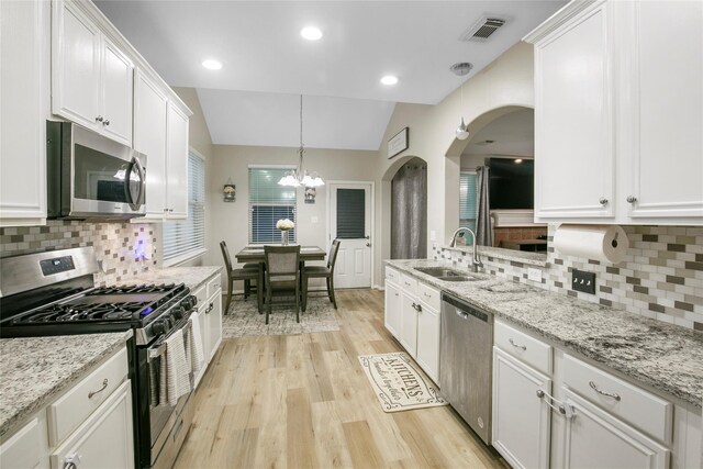 5732 Montclair Hill Ln, Rosharon, TX 77583 - kitchen featuring appliances with stainless steel finishes, arched walkways, a chandelier, white cabinetry, and light wood finished floors