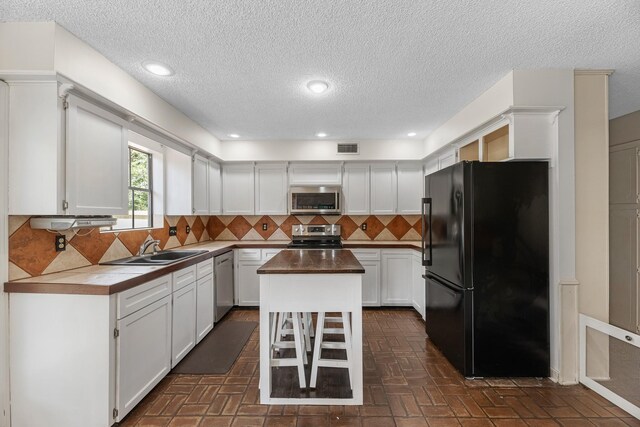 457 Monticello Park, Conroe, TX 77302 - kitchen with appliances with stainless steel finishes, a sink, white cabinetry, tasteful backsplash, and a textured ceiling
