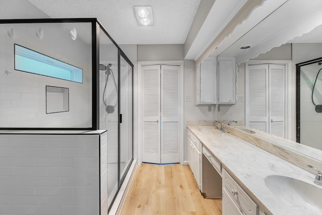 457 Monticello Park, Conroe, TX 77302 - bathroom featuring a closet, double vanity, a shower stall, wood finished floors, and a textured ceiling