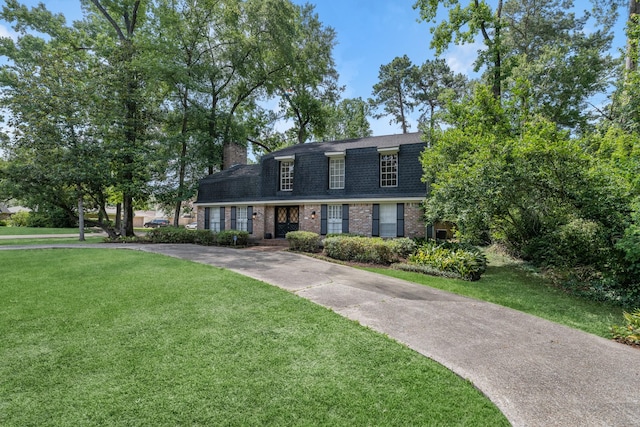 457 Monticello Park, Conroe, TX 77302 - colonial inspired home with a shingled roof, brick siding, a front yard, a chimney, and concrete driveway