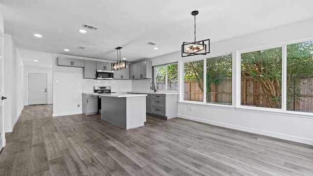 8603 Twisting Vine Ln, Houston, TX 77040 - kitchen with gray cabinetry, appliances with stainless steel finishes, a chandelier, light countertops, and wood finished floors