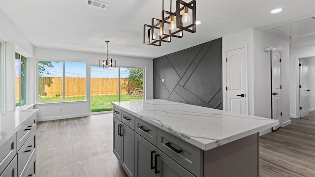 8603 Twisting Vine Ln, Houston, TX 77040 - kitchen featuring gray cabinets, baseboards, a center island, light stone counters, and wood finished floors
