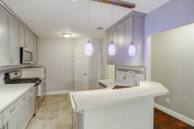 7112 Ave L, Houston, TX 77011 - kitchen featuring appliances with stainless steel finishes, a sink, backsplash, and a peninsula