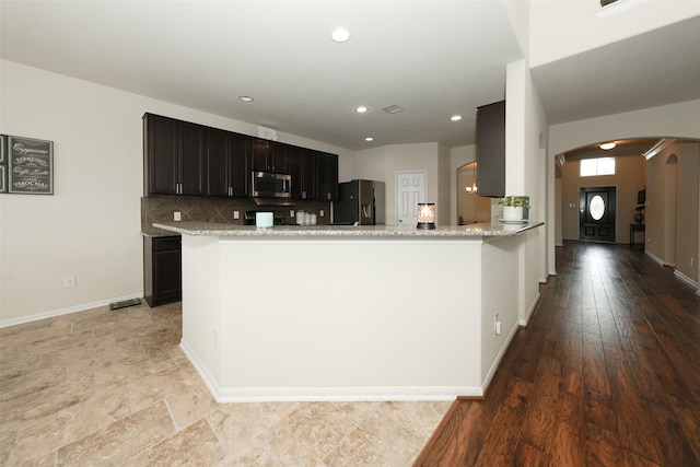 3314 Tall Sycamore Trl, Katy, TX 77493 - kitchen featuring fridge with ice dispenser, stainless steel microwave, arched walkways, backsplash, and baseboards