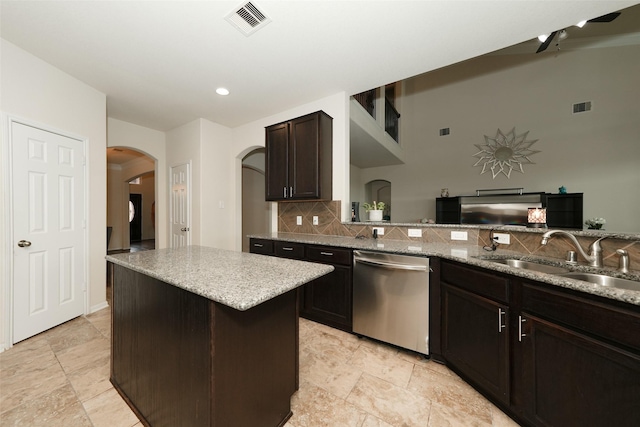 3314 Tall Sycamore Trl, Katy, TX 77493 - kitchen with stainless steel dishwasher, a sink, arched walkways, tasteful backsplash, and light stone countertops