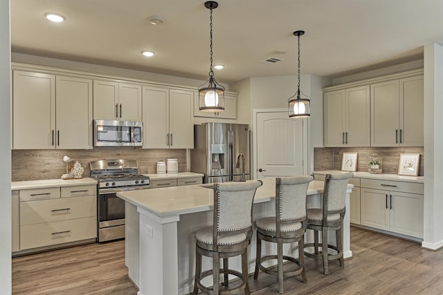 109 Pepper Grass Pl, Montgomery, TX 77316 - kitchen featuring appliances with stainless steel finishes, tasteful backsplash, light countertops, a kitchen island with sink, and a kitchen bar