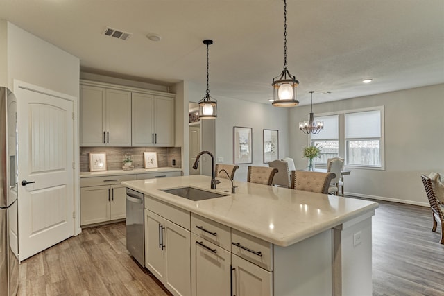 109 Pepper Grass Pl, Montgomery, TX 77316 - kitchen featuring a sink, stainless steel appliances, tasteful backsplash, light wood-type flooring, and a kitchen island with sink