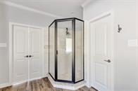 27684 Rio Blanco Dr, Splendora, TX 77372 - bathroom featuring a stall shower, wood finished floors, and crown molding