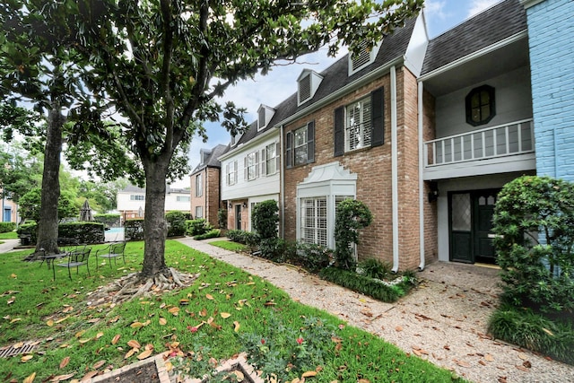405 N Post Oak Ln Unit 405, Houston, TX 77024 - view of property exterior with brick siding, a lawn, and roof with shingles