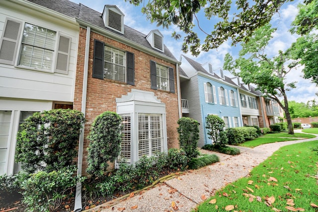 405 N Post Oak Ln Unit 405, Houston, TX 77024 - view of home's exterior with brick siding, a yard, and roof with shingles