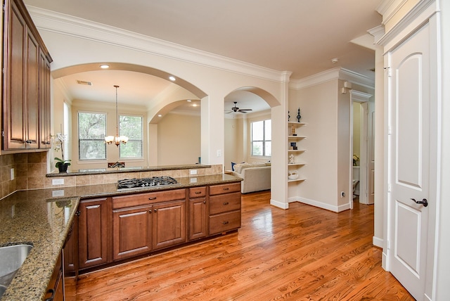 321 W 26th St Unit A, Houston, TX 77008 - kitchen featuring stainless steel gas stovetop, brown cabinets, a peninsula, decorative backsplash, and ornamental molding