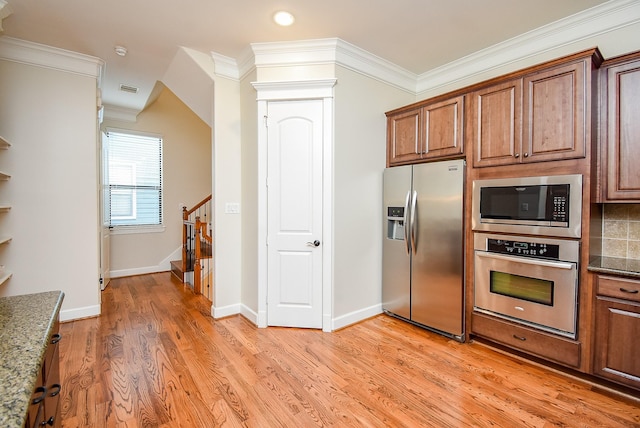 321 W 26th St Unit A, Houston, TX 77008 - kitchen with appliances with stainless steel finishes, crown molding, light wood-type flooring, dark stone countertops, and baseboards