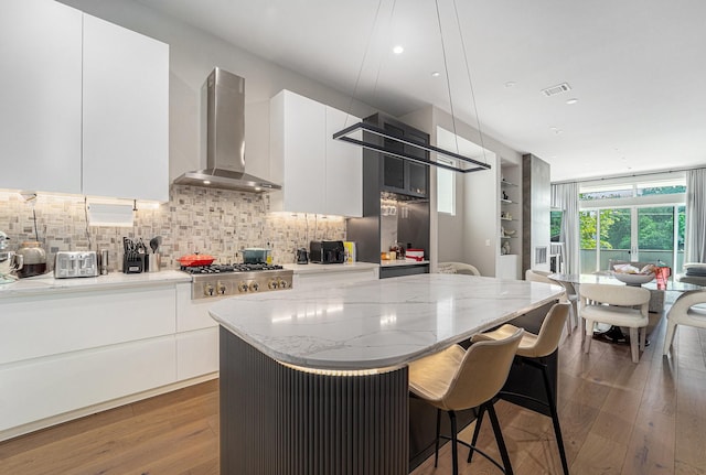 1116 Peden St, Houston, TX 77006 - kitchen with island exhaust hood, modern cabinets, tasteful backsplash, a kitchen island, and wood finished floors