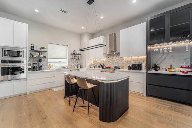 1116 Peden St, Houston, TX 77006 - kitchen featuring stainless steel appliances, wall chimney range hood, modern cabinets, backsplash, and recessed lighting