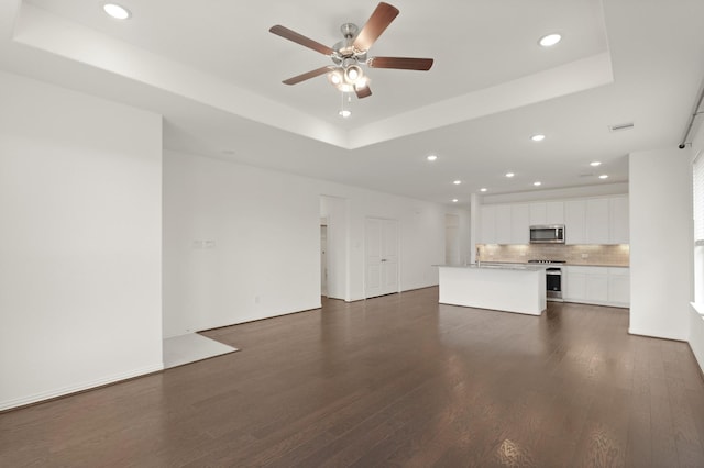 7919 Chantilly Mnr, Fulshear, TX 77441 - unfurnished living room featuring a raised ceiling, recessed lighting, a ceiling fan, and dark wood-type flooring