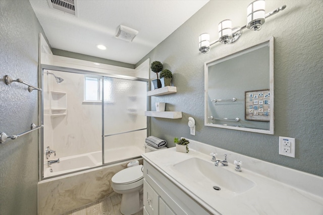 219 Bora Bora Dr, Tiki Island, TX 77554 - bathroom with vanity, a textured wall, toilet, bath / shower combo with glass door, and wood finished floors