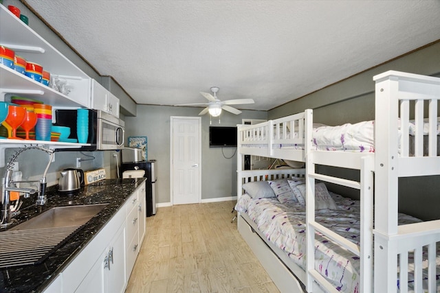 219 Bora Bora Dr, Tiki Island, TX 77554 - bedroom with a sink, light wood-style flooring, baseboards, and a textured ceiling