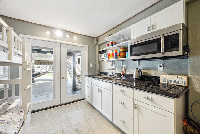 219 Bora Bora Dr, Tiki Island, TX 77554 - kitchen with stainless steel microwave, french doors, a sink, white cabinets, and light wood-type flooring