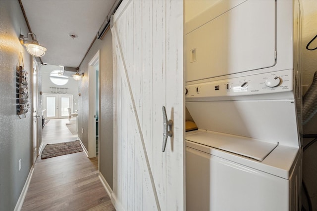 219 Bora Bora Dr, Tiki Island, TX 77554 - laundry room with stacked washer and clothes dryer, light wood-style flooring, and baseboards