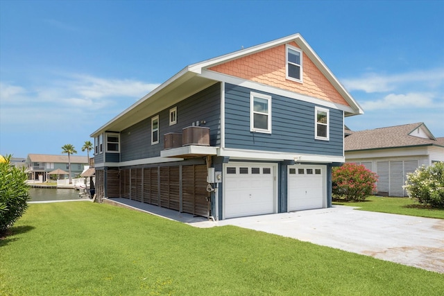 219 Bora Bora Dr, Tiki Island, TX 77554 - back of house with a lawn, a garage, concrete driveway, and a water view