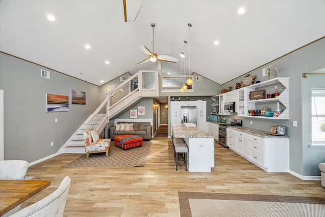219 Bora Bora Dr, Tiki Island, TX 77554 - kitchen with stainless steel appliances, open shelves, white cabinets, a kitchen bar, and open floor plan