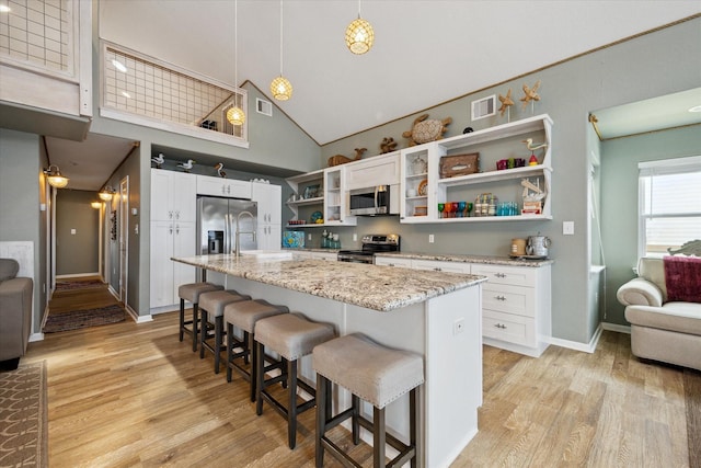 219 Bora Bora Dr, Tiki Island, TX 77554 - kitchen with open shelves, stainless steel appliances, high vaulted ceiling, light wood-type flooring, and a kitchen breakfast bar