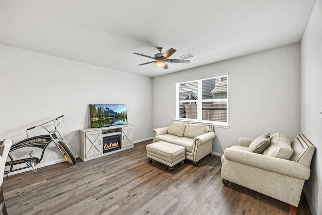 3919 Faletti Dr, Katy, TX 77493 - living room with wood finished floors, a ceiling fan, a warm lit fireplace, and baseboards