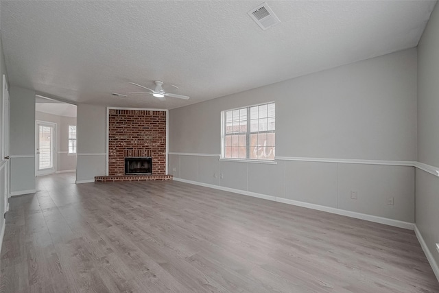 8621 Rustling Lvs Dr, Houston, TX 77083 - unfurnished living room with a ceiling fan, a textured ceiling, wood finished floors, a brick fireplace, and baseboards