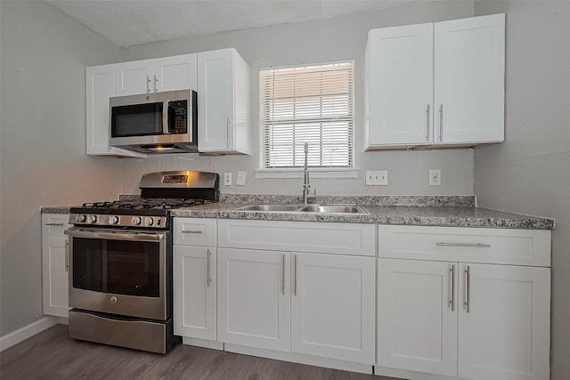 8621 Rustling Lvs Dr, Houston, TX 77083 - kitchen with stainless steel appliances, a sink, wood finished floors, white cabinets, and baseboards
