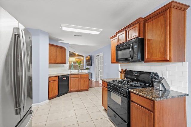 9822 Garnet Springs Dr, Iowa Colony, TX 77583 - kitchen featuring black appliances, a sink, decorative backsplash, dark stone counters, and vaulted ceiling