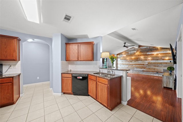 9822 Garnet Springs Dr, Iowa Colony, TX 77583 - kitchen featuring black dishwasher, a sink, wood walls, arched walkways, and dark stone counters