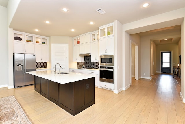 22911 Pearl Glen Dr, Richmond, TX 77469 - kitchen featuring stainless steel appliances, a sink, decorative backsplash, light countertops, and an island with sink