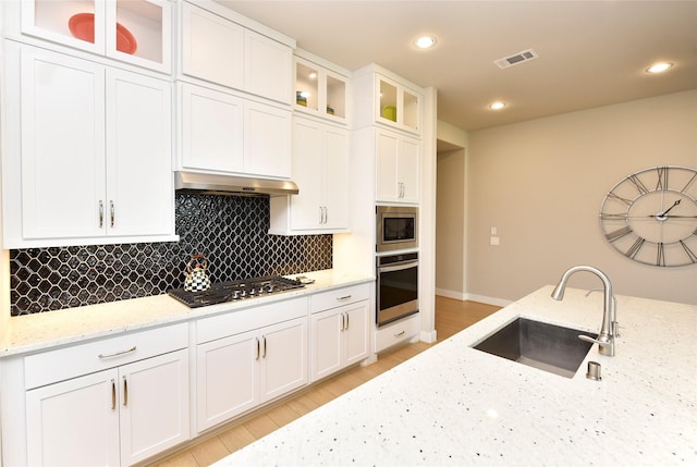 22911 Pearl Glen Dr, Richmond, TX 77469 - kitchen with stainless steel appliances, a sink, under cabinet range hood, tasteful backsplash, and white cabinets