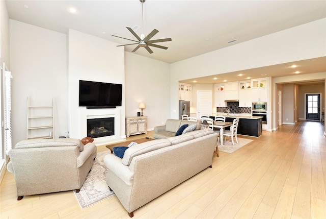 22911 Pearl Glen Dr, Richmond, TX 77469 - living room featuring a glass covered fireplace, ceiling fan, light wood-type flooring, recessed lighting, and baseboards