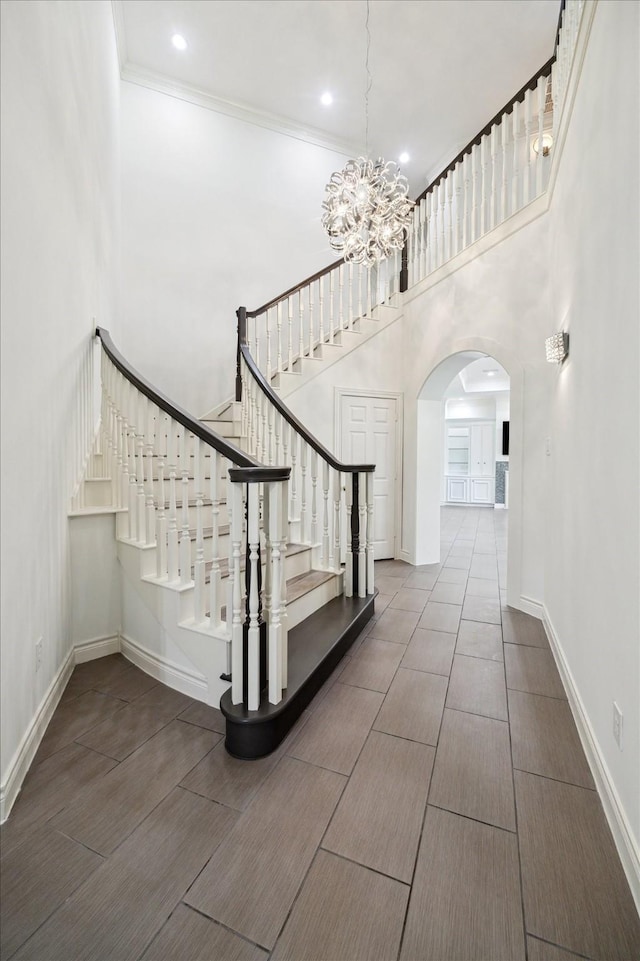4111 Thistle Hill Ct, Sugar Land, TX 77479 - stairway with arched walkways, a chandelier, a high ceiling, baseboards, and wood finished floors