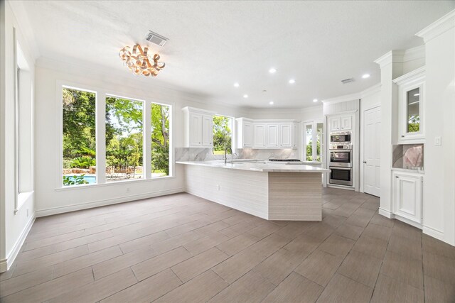 4111 Thistle Hill Ct, Sugar Land, TX 77479 - kitchen with light countertops, stainless steel appliances, a peninsula, tasteful backsplash, and crown molding