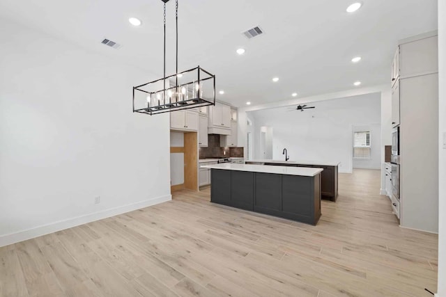 12834 Forest Garden Ct, Conroe, TX 77302 - kitchen featuring a large island, light wood-style floors, recessed lighting, white cabinets, and light countertops