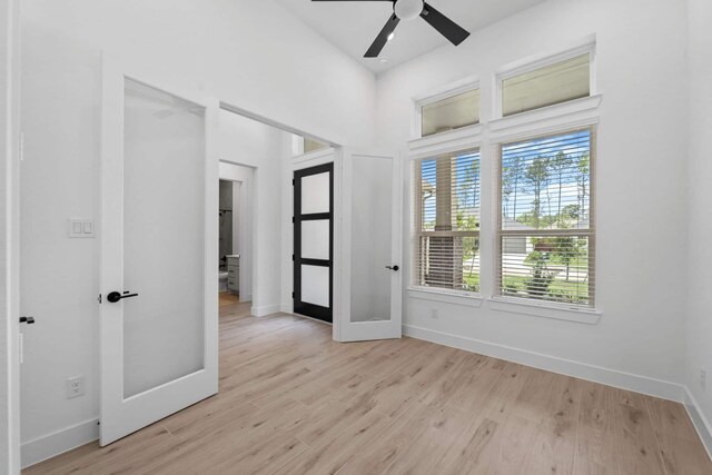 12834 Forest Garden Ct, Conroe, TX 77302 - empty room featuring french doors, baseboards, light wood-style flooring, ceiling fan, and a towering ceiling