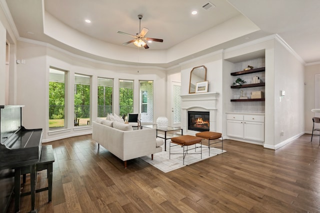 4051 Ashland Woods Dr, Spring, TX 77386 - living area with a tray ceiling, ceiling fan, dark wood-style flooring, a glass covered fireplace, and ornamental molding