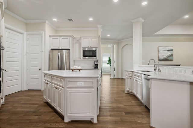 4051 Ashland Woods Dr, Spring, TX 77386 - kitchen featuring appliances with stainless steel finishes, a sink, a center island with sink, ornate columns, and white cabinets