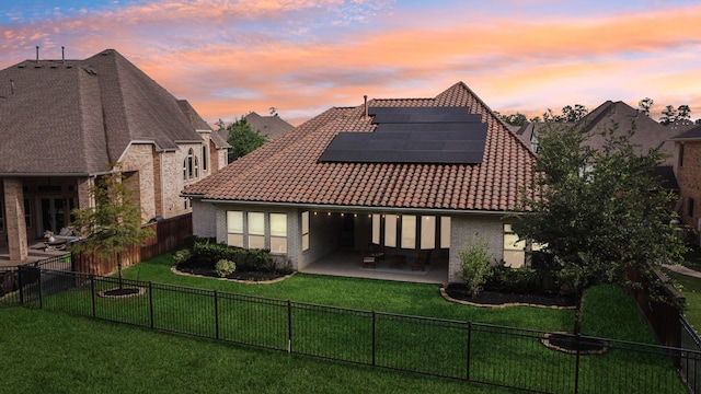 4051 Ashland Woods Dr, Spring, TX 77386 - back of property at dusk with a patio, roof mounted solar panels, a tile roof, and brick siding